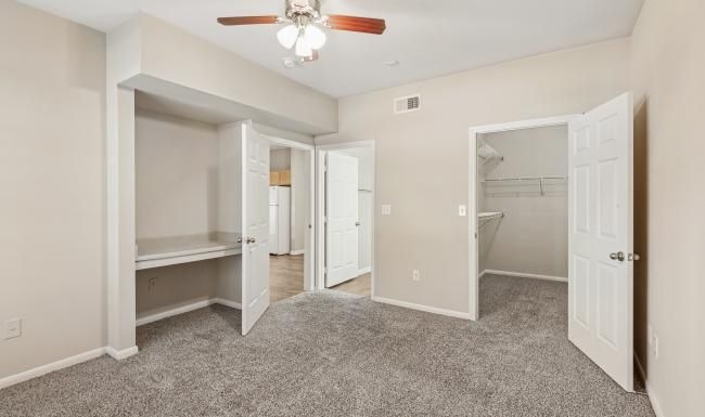 a bedroom with closets, carpet and a fan